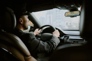 A professional, uniformed driver navigating city streets in a luxury vehicle, illustrating how chauffeur services reduce travel fatigue by handling the driving.